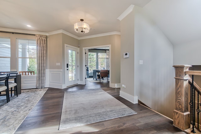 foyer entrance featuring dark wood-type flooring, a chandelier, crown molding, and lofted ceiling