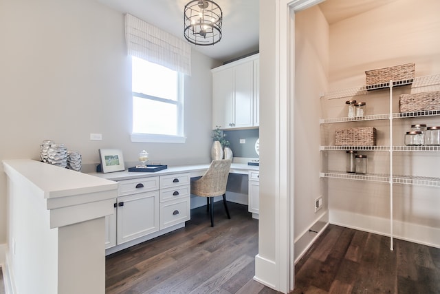 home office with dark wood-type flooring and built in desk