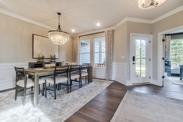 dining room featuring dark wood-type flooring, ornamental molding, a notable chandelier, and a healthy amount of sunlight