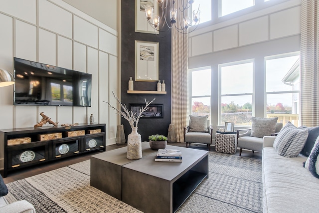 living room with a towering ceiling, wood-type flooring, and an inviting chandelier