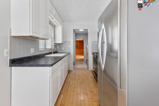 kitchen featuring stainless steel fridge, sink, electric range, light hardwood / wood-style flooring, and white cabinets