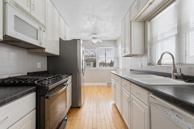 kitchen with white cabinetry, sink, ceiling fan, light hardwood / wood-style flooring, and white appliances