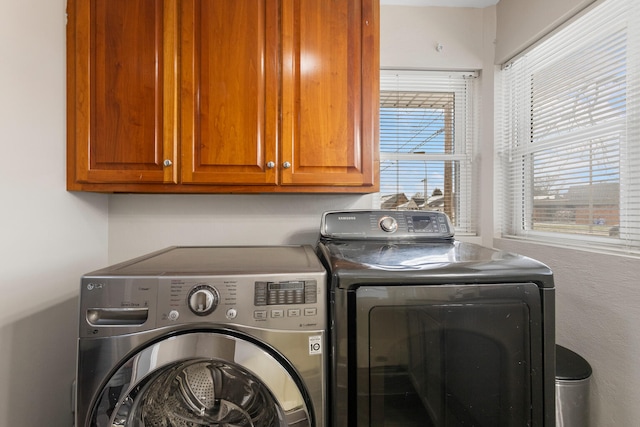 laundry area with washing machine and clothes dryer and cabinets