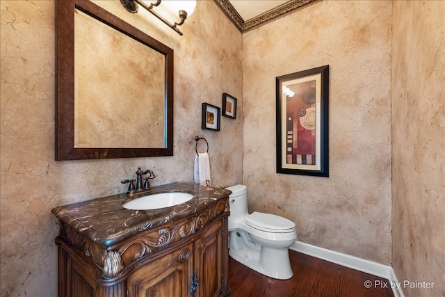 half bathroom with vanity, wood finished floors, toilet, and baseboards