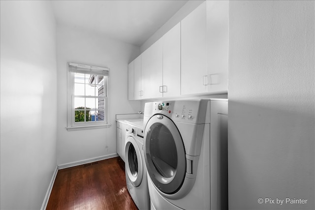 clothes washing area featuring separate washer and dryer, dark wood finished floors, cabinet space, and baseboards