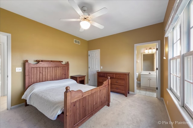 bedroom with visible vents, light carpet, baseboards, and ensuite bathroom