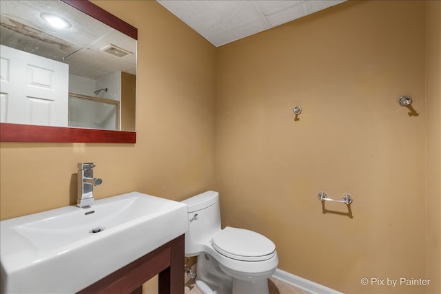 bathroom with a shower, visible vents, toilet, vanity, and baseboards