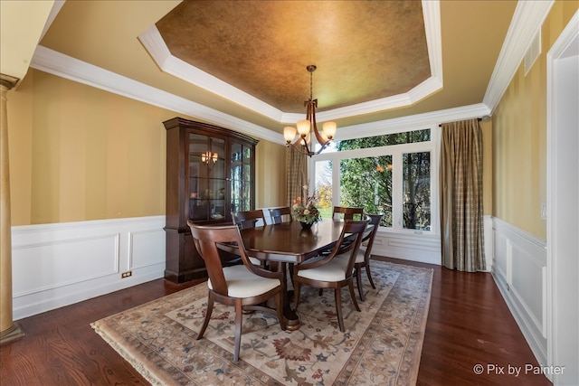 dining room with wood finished floors, ornamental molding, wainscoting, a tray ceiling, and an inviting chandelier