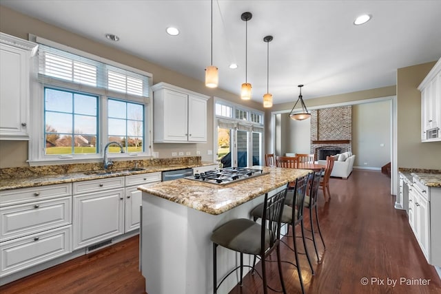 kitchen featuring a large fireplace, a sink, visible vents, white cabinetry, and appliances with stainless steel finishes