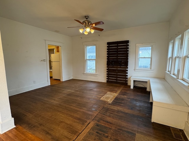 interior space featuring ceiling fan, white fridge, dark hardwood / wood-style flooring, and multiple windows