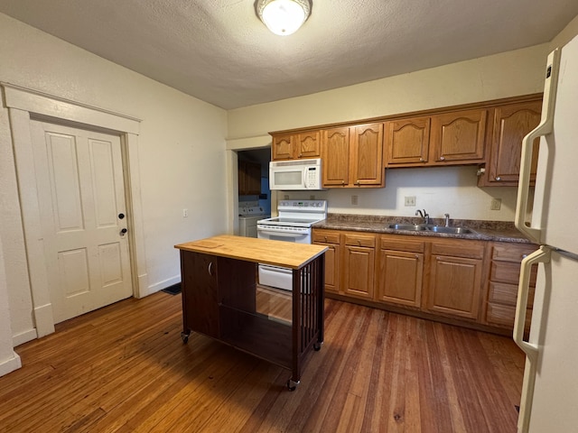 kitchen with white appliances, dark wood-type flooring, wooden counters, sink, and a textured ceiling