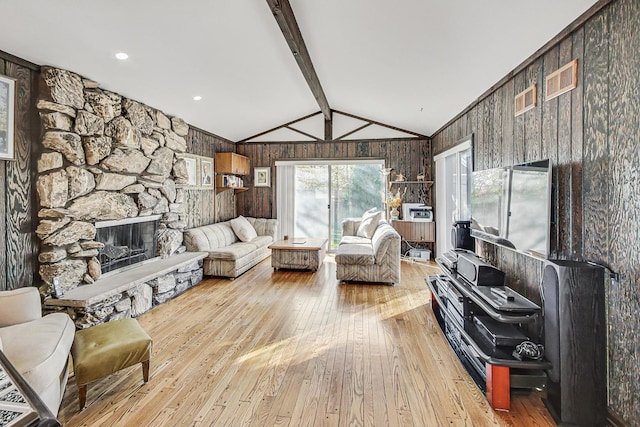 living room with wood walls, a fireplace, lofted ceiling with beams, and light hardwood / wood-style floors