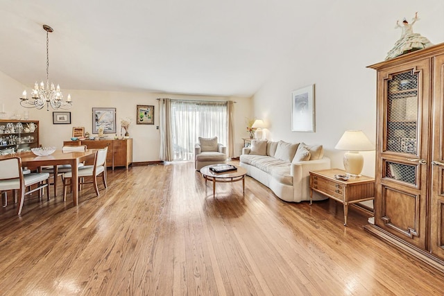 living room with light hardwood / wood-style floors, vaulted ceiling, and a notable chandelier