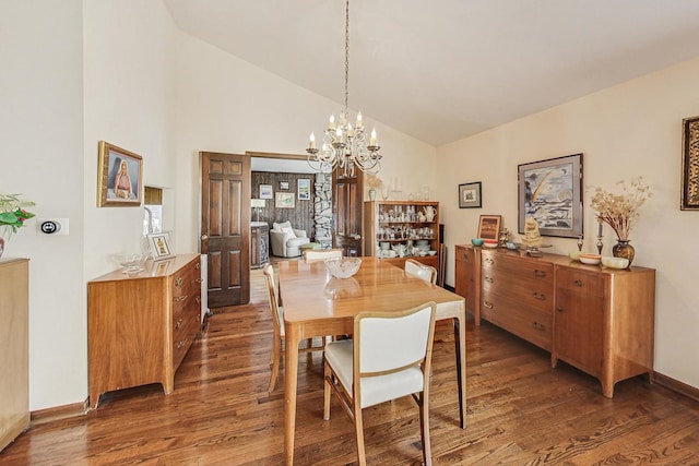 dining area featuring high vaulted ceiling, dark hardwood / wood-style floors, and an inviting chandelier