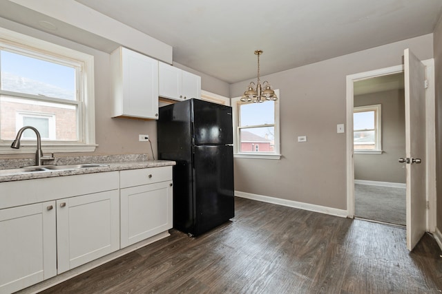 kitchen with white cabinets, black refrigerator, sink, and a wealth of natural light