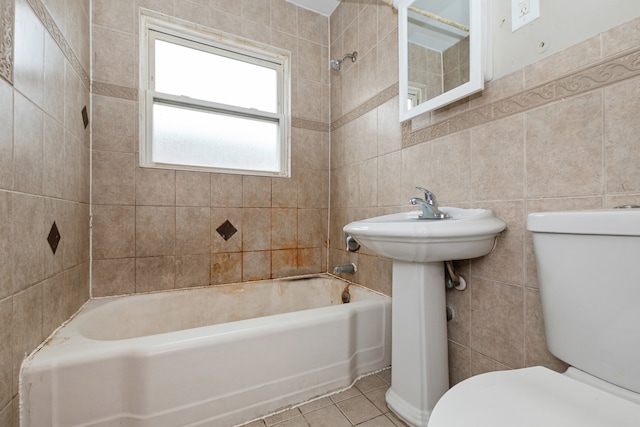 bathroom with tile patterned floors, tiled shower / bath combo, toilet, and tile walls