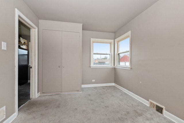 unfurnished bedroom with light colored carpet and a closet