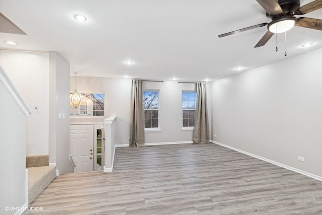 entrance foyer with ceiling fan with notable chandelier and light hardwood / wood-style floors