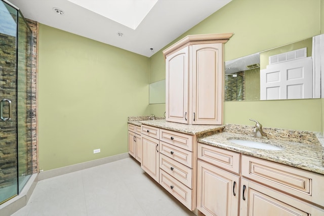 bathroom featuring tile patterned flooring, vanity, a skylight, and a shower with door