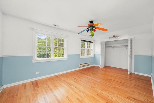 unfurnished bedroom with ceiling fan, a closet, light wood-type flooring, and a baseboard heating unit