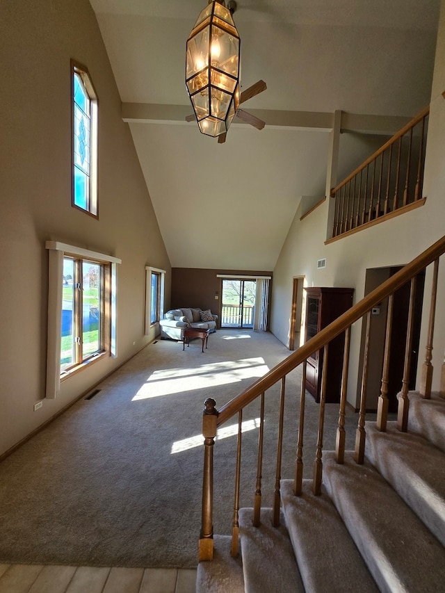 stairway with high vaulted ceiling and carpet floors