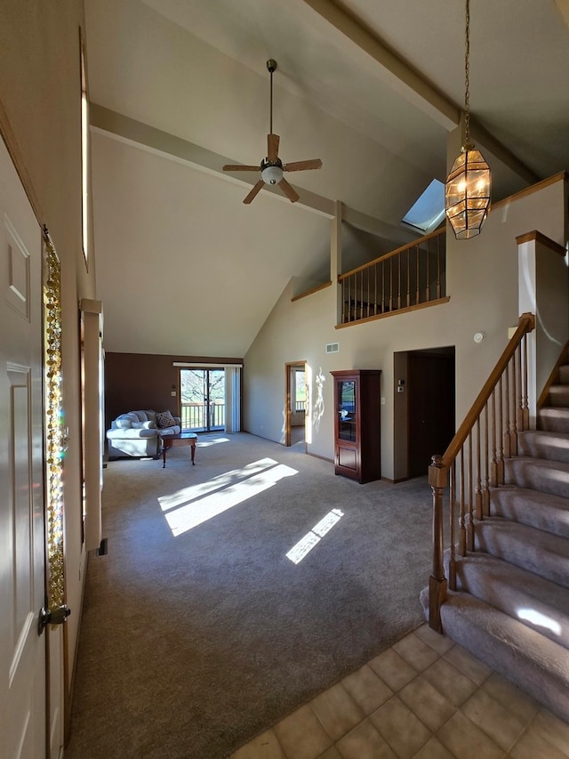 unfurnished living room with high vaulted ceiling, carpet, a skylight, and ceiling fan