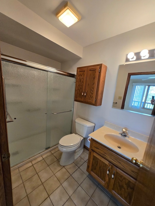 bathroom featuring toilet, vanity, tile patterned floors, and a shower with door