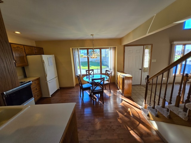 interior space with pendant lighting, plenty of natural light, white fridge, and black / electric stove