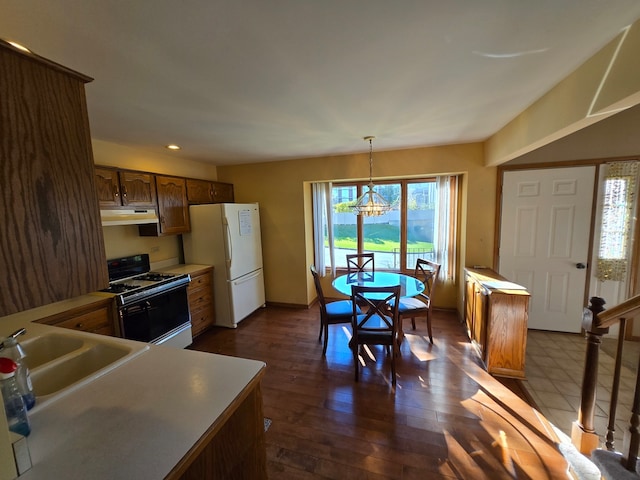 kitchen with a chandelier, pendant lighting, sink, dark wood-type flooring, and white appliances