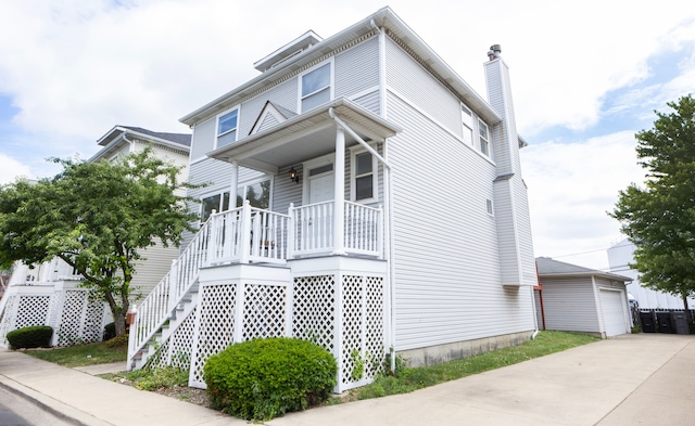 view of front of house featuring a garage, a porch, and an outbuilding