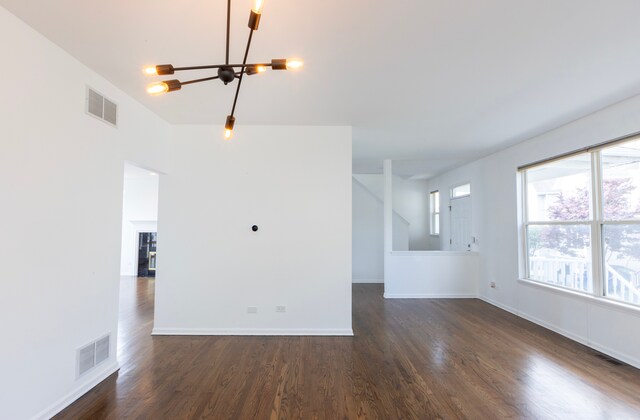 unfurnished living room featuring a chandelier and dark hardwood / wood-style floors