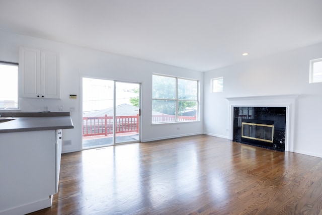 unfurnished living room with a wealth of natural light, dark wood-type flooring, and a tile fireplace