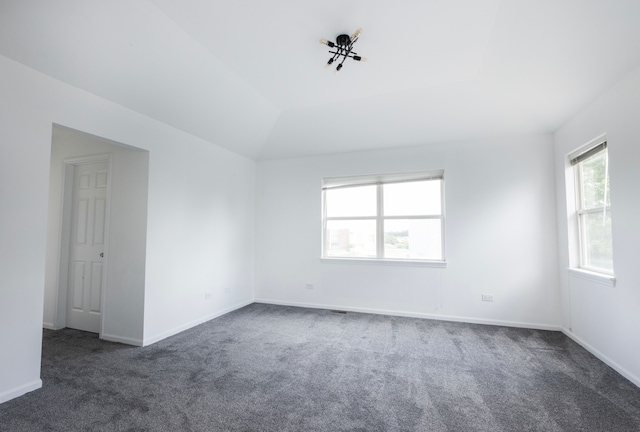 unfurnished room with lofted ceiling and dark carpet