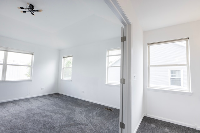 spare room featuring ceiling fan and dark carpet