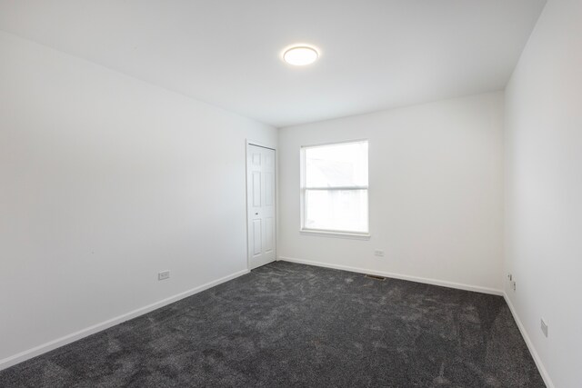 spare room with dark colored carpet