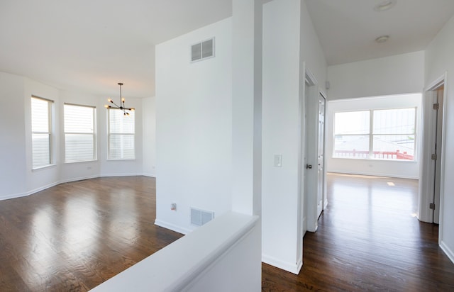 hall featuring dark hardwood / wood-style flooring, a healthy amount of sunlight, and a chandelier