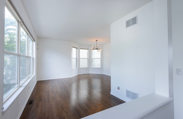 empty room with a chandelier and dark hardwood / wood-style flooring