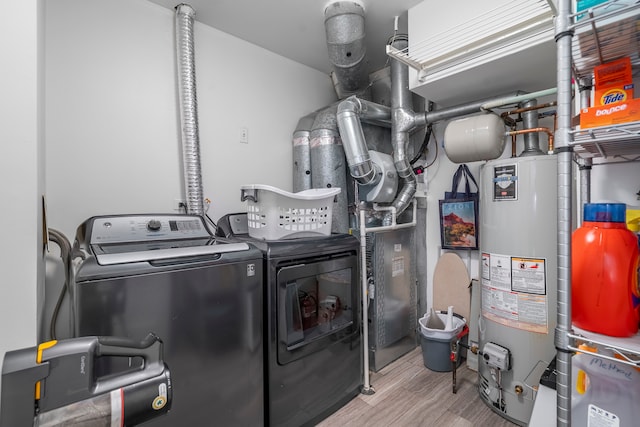 clothes washing area with washer and clothes dryer, gas water heater, and light hardwood / wood-style floors