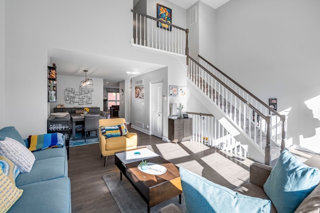 living room with dark wood-type flooring and a high ceiling