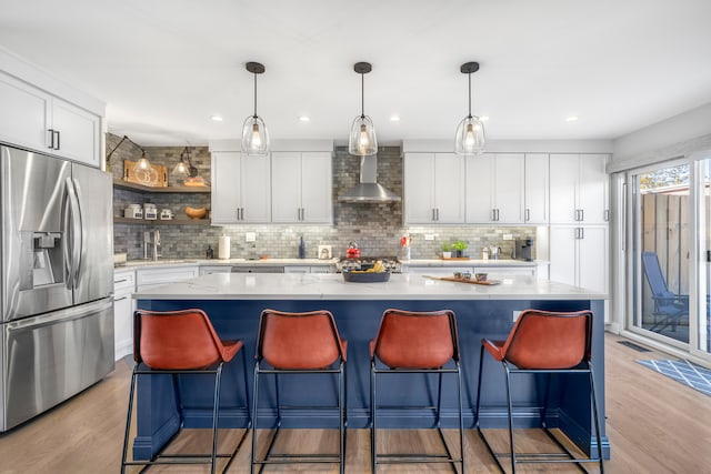 kitchen with white cabinets, stainless steel fridge, light hardwood / wood-style flooring, and a center island