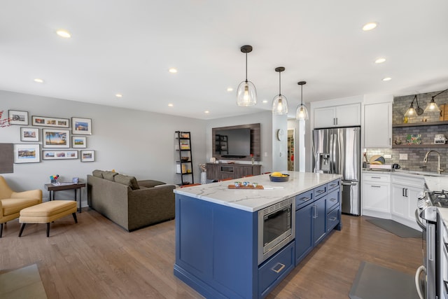 kitchen with stainless steel appliances, white cabinetry, blue cabinets, dark wood-type flooring, and a center island