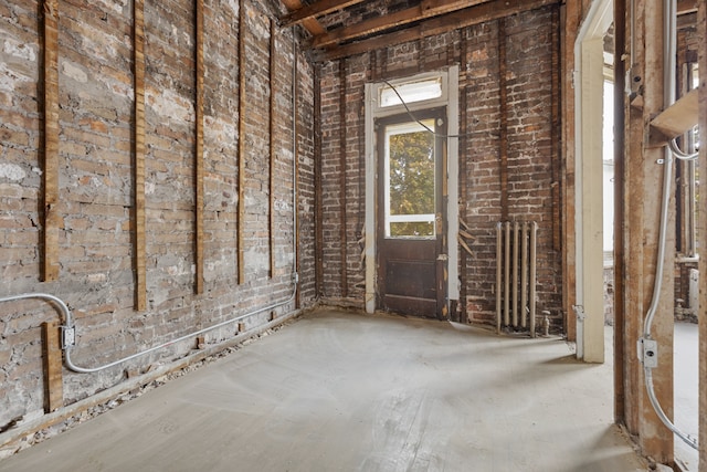 miscellaneous room with radiator heating unit and brick wall