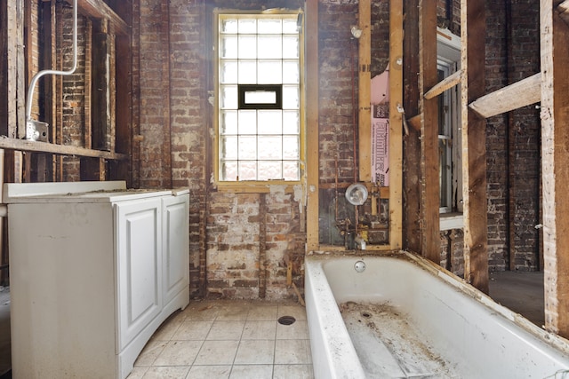 bathroom with tile patterned floors, brick wall, and a bathtub