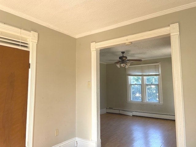 spare room featuring hardwood / wood-style flooring, ceiling fan, ornamental molding, baseboard heating, and a textured ceiling