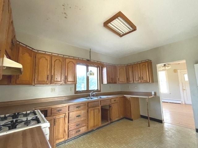 kitchen with plenty of natural light, white gas range, sink, and a baseboard radiator