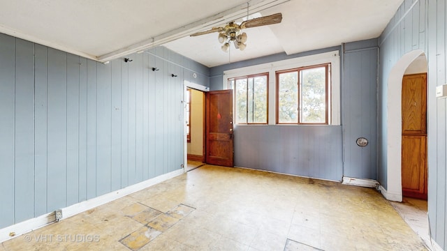 unfurnished bedroom with wooden walls and ceiling fan