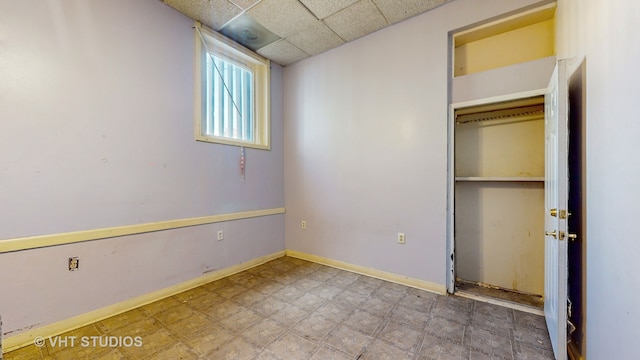 unfurnished bedroom with a closet and a drop ceiling