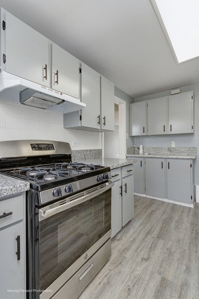 kitchen with decorative backsplash, light hardwood / wood-style floors, and stainless steel range with gas stovetop