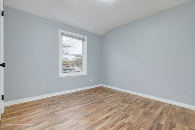 unfurnished room with light hardwood / wood-style floors and lofted ceiling