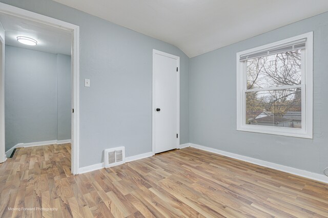 unfurnished bedroom featuring lofted ceiling and light wood-type flooring